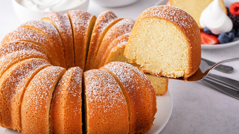 A pound cake baked made in a bundt pan with icing sugar being served in slices.