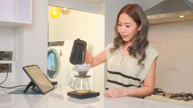 A woman makes a pour-over on a scale in her own kitchen