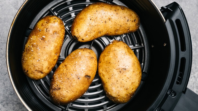 Four potatoes in an air fryer basket