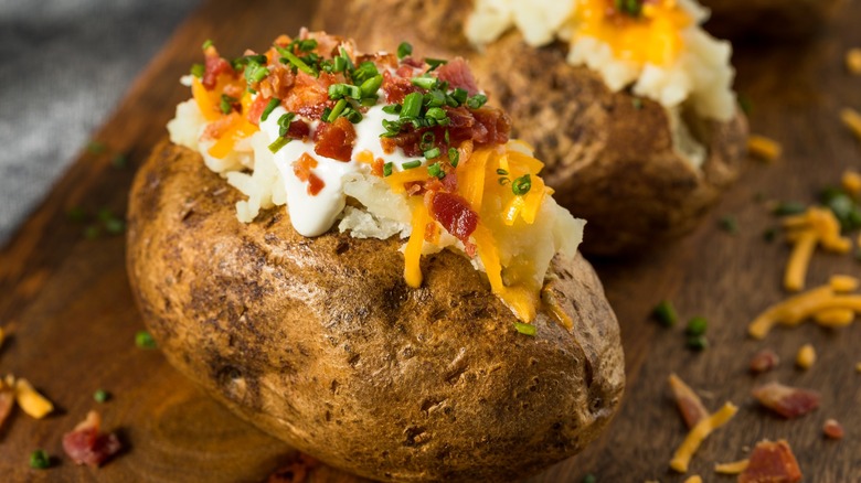 Loaded baked potatoes on wood board