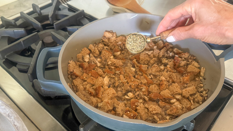 hand adding spices to pan