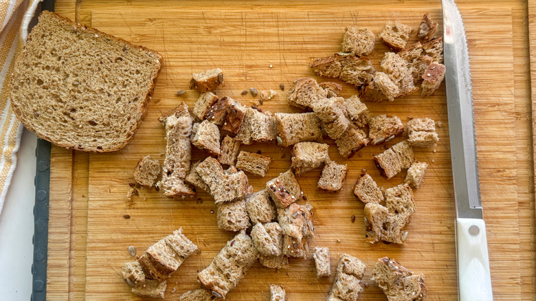 cubed bread on wooden board with knife