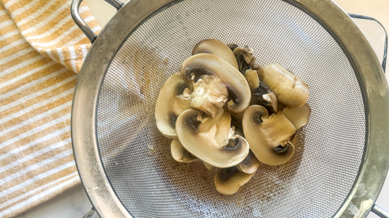 Sliced mushrooms in mesh sieve