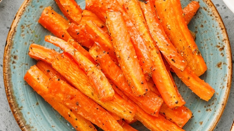 Plate of roasted carrot sticks with seasoning.