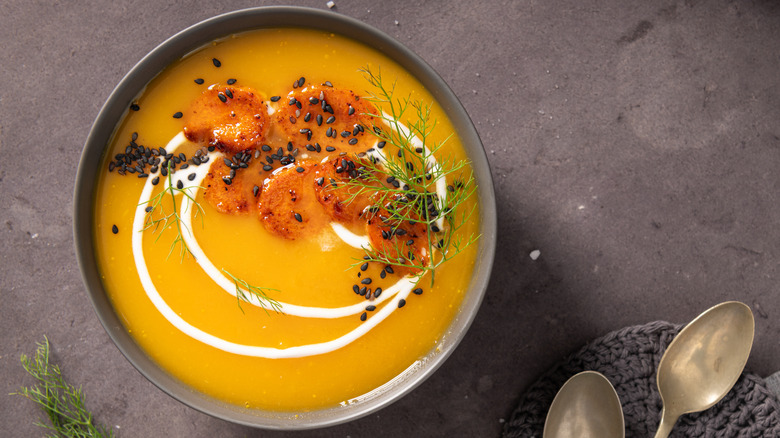 Soup garnished with croutons, seeds, and herb
