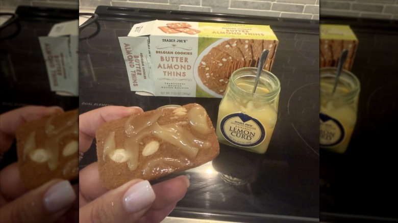 A hand holds a Trader Joe's Butter Almond Thins cookie topped with lemon curd