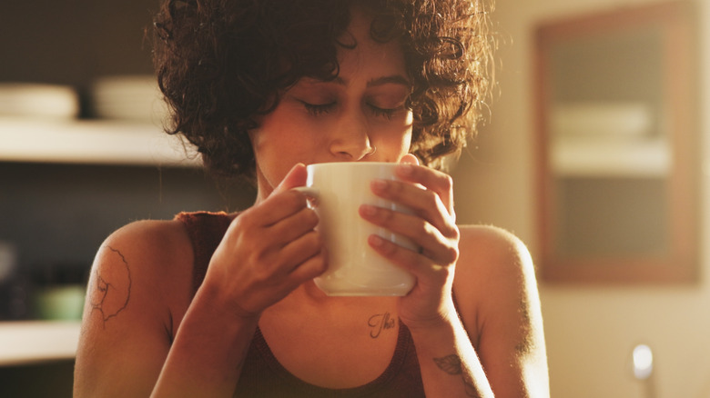 A woman lifts a warm cup of coffee to her mouth