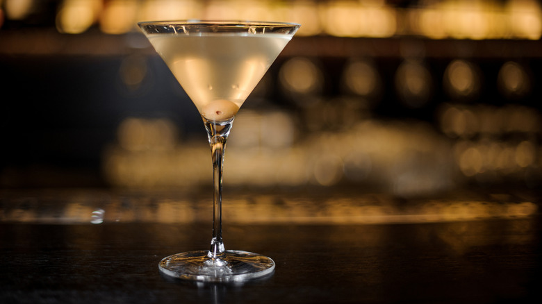 A martini cocktail with an olive on a bar