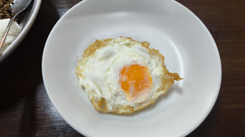 Crispy fried egg on white plate with browned edges.