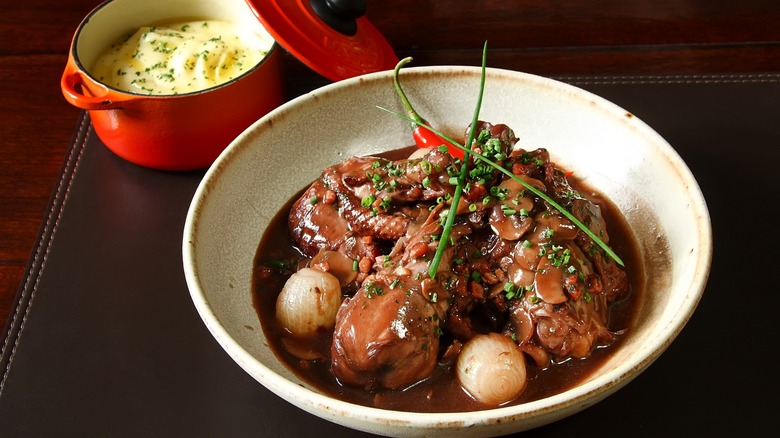 Classic French coq au vin in a white bowl with fresh herbs