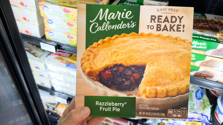 Someone holding a Marie Callender's frozen pie in the supermarket