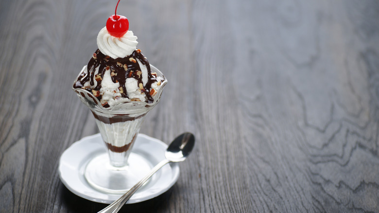 Hot fudge sundae in tall glass with spoon