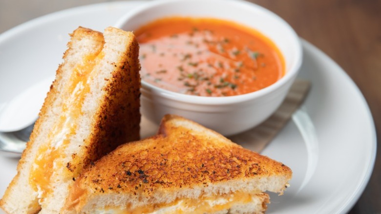 Grilled cheese with tomato soup on a white glass plate