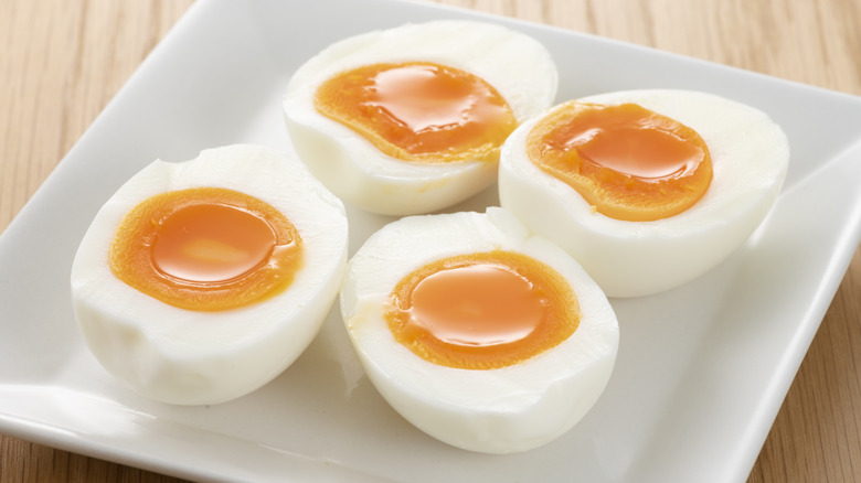 Halved soft-boiled eggs on white plate