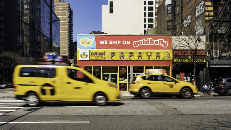 Two taxis drive by Papaya King in New York City