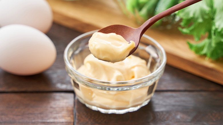 Wooden spoon getting mayonnaise out of bowl