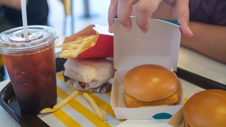 A hand opening a Filet-o-Fish from McDonald's.