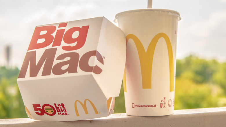 A McDonald's Big Mac Box leaning on a McDonald's drink