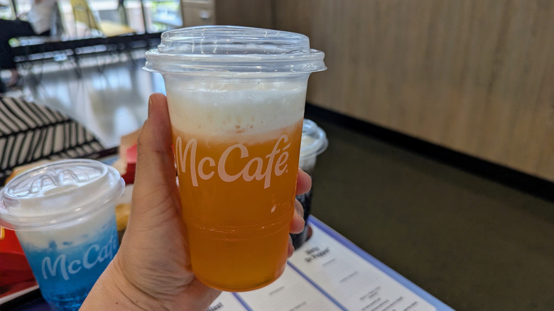 Hand holding McDonald's Orange Dream soda.