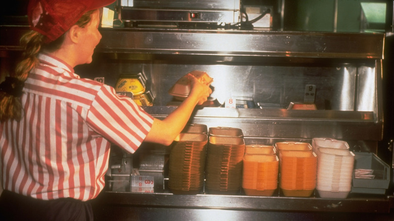A vintage photo of a McDonald's employee boxing up to-go orders in Styrofoam containers