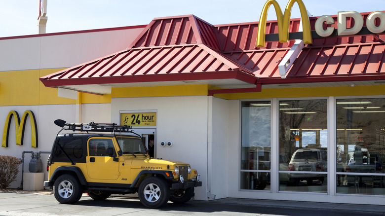 A yellow jeep pick-up ordering at the drive-thru window at McDonald's.