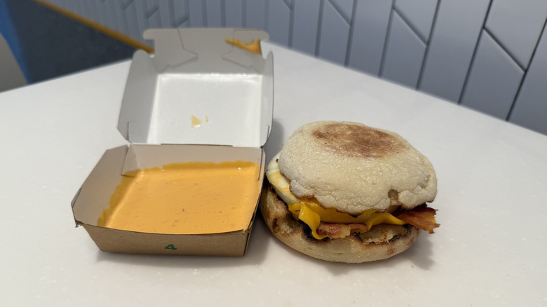 a box of sauce and Spicy McMuffin with bacon