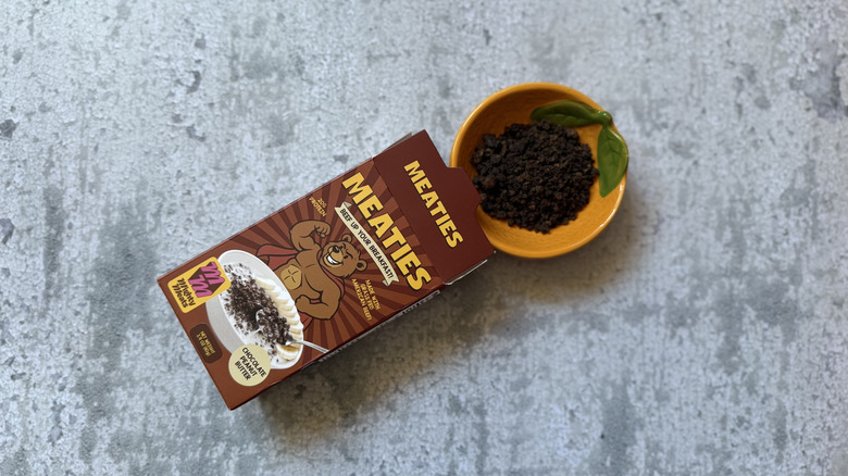 Chocolate Peanut Butter Meaties Cereal package and some in a yellow bowl with a green leaf on it