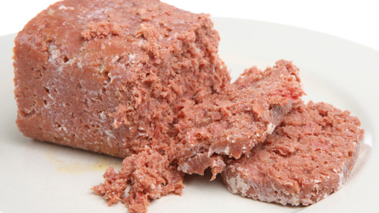 Canned corned beef removed from the can, sliced, and resting on a white plate