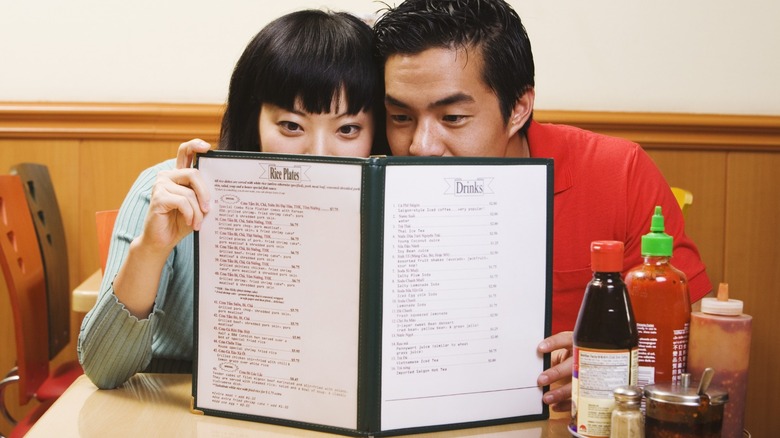 A couple at a restaurant looking closely at a menu.