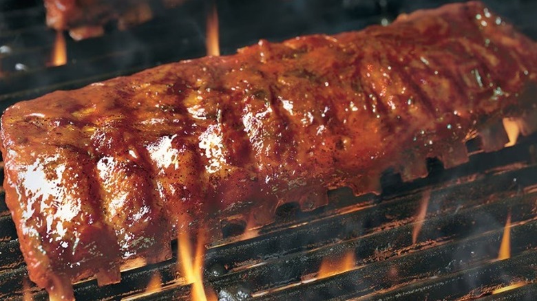 A rack of LongHorn's Baby Back Ribs sitting on an open flame grill.