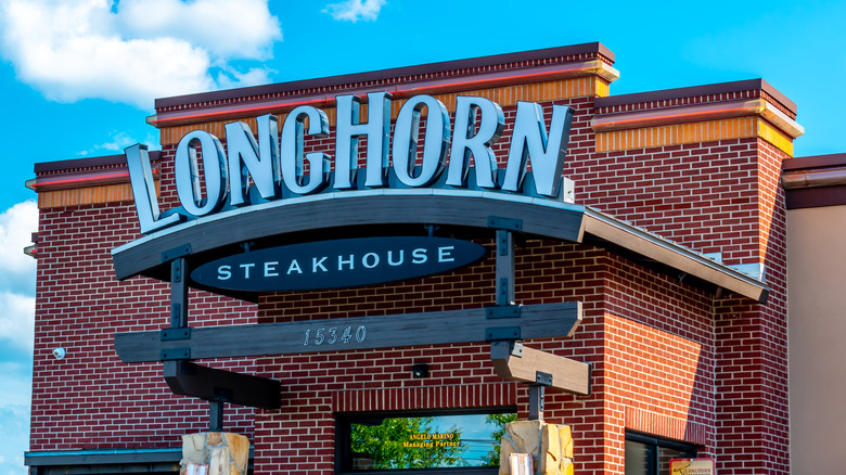 The exterior of a LongHorn Steakhouse restaurant against a blue sky background.