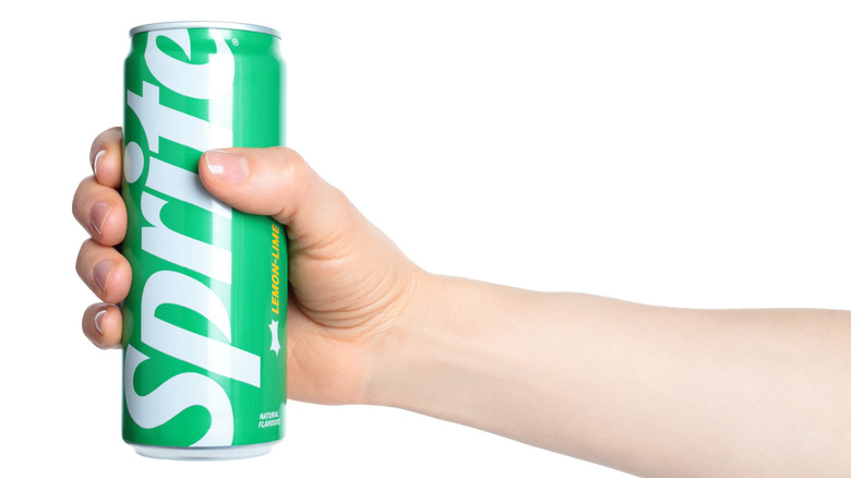 Hand holding up can of Sprite soda