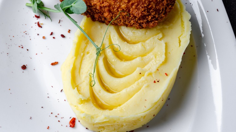 Restaurant-style mashed potatoes on a white plate with garnish.