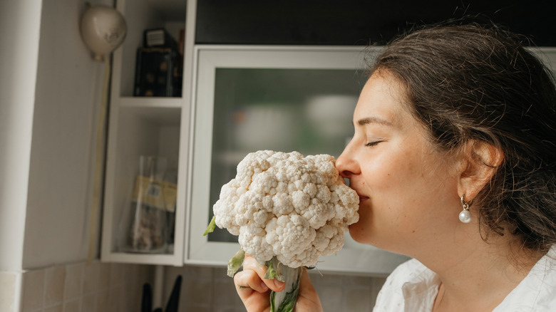 Woman inhales deeply from a cauliflower head