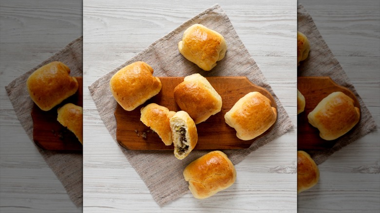 Home-baked Beef Russian Bierocks on a rustic wooden board on a white wooden background, top view. Flat lay, overhead, from above.