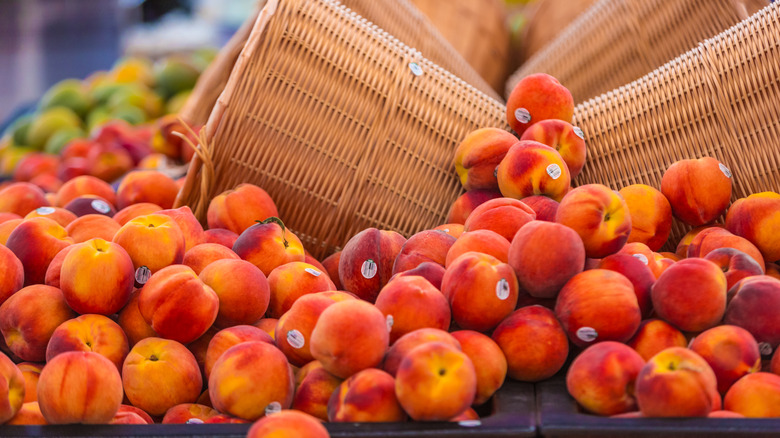 Baskets spilling fresh peaches in supermarket produce aisle display