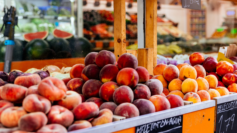 Produce section in grocery store showing different varieties of peaches for sale