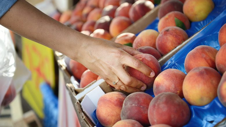 Hand squeezing a peach in display