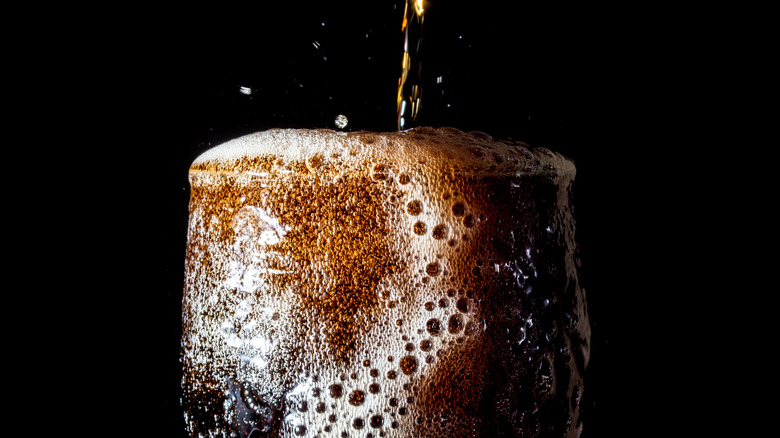 glass of bubbly cola overflowing