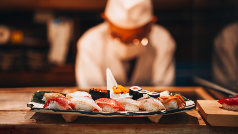 Sushi chef working behind a plate of sushi on counter