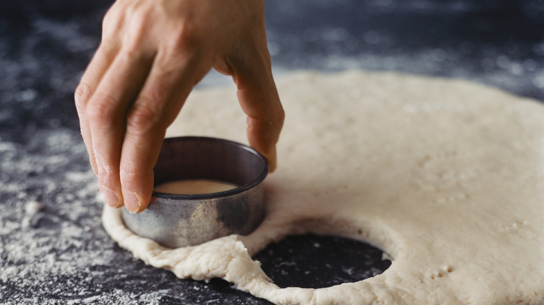 Hand using biscuit cutter to cut out biscuits