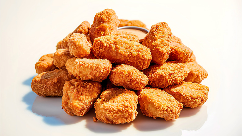 A stack of fresh chicken nuggets and sauce sitting on a surface