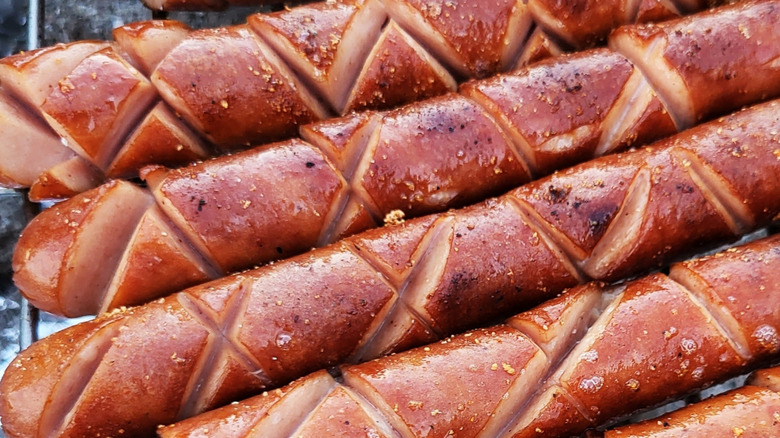 Close-up shot of scored hot dogs on a grill