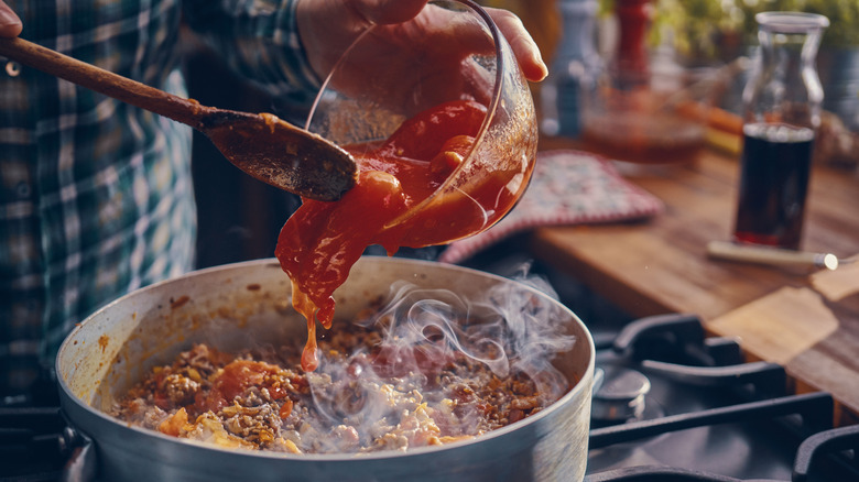 Preparing homemade spaghetti bolognese in domestic kitchen.