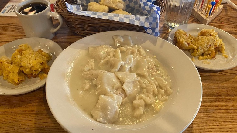 Plate with of chicken and dumplings alongside plates of hash brown casserole from Cracker Barrel