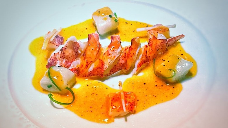 Sliced lobster on a white plate with a yellow sauce