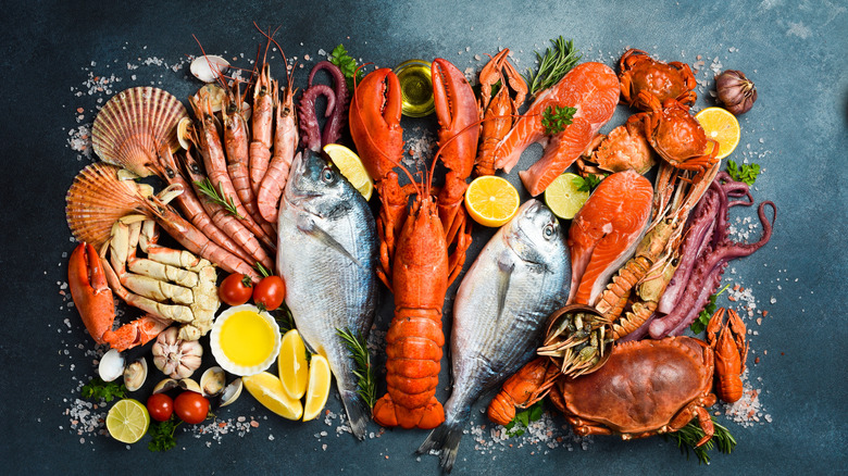 An assortment of fresh, whole seafood including lobster, crab, and prawns on a gray counter