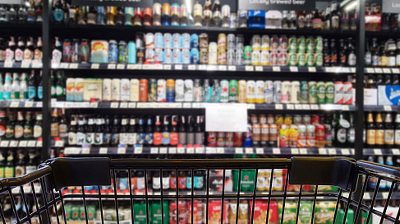 Blurred background of a grocery store beer aisle with cart in foreground