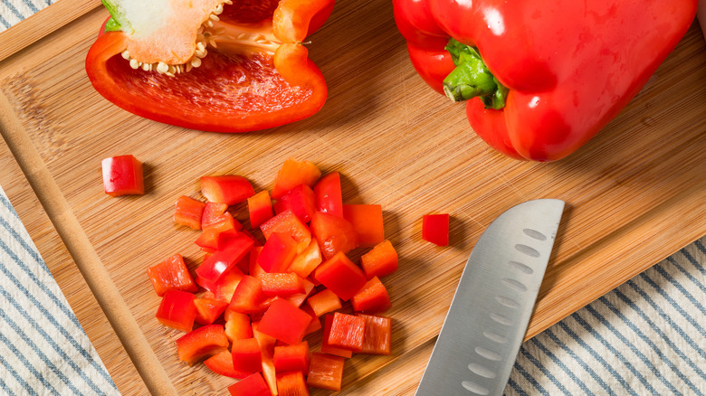 Red bell peppers on a cutting board next to a knife