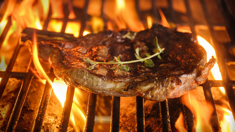 Steak cooking on a grill over flames